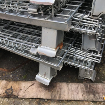 Used collapsible pallet mesh stillage cages stacked up.